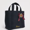 Harrods 藍色重磅厚帆布手提包正面，展示英國勳章軍服絲帶花與亮片徽章細節